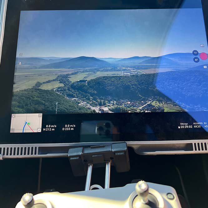 A private investigator operates a drone at high altitude to monitor a nature